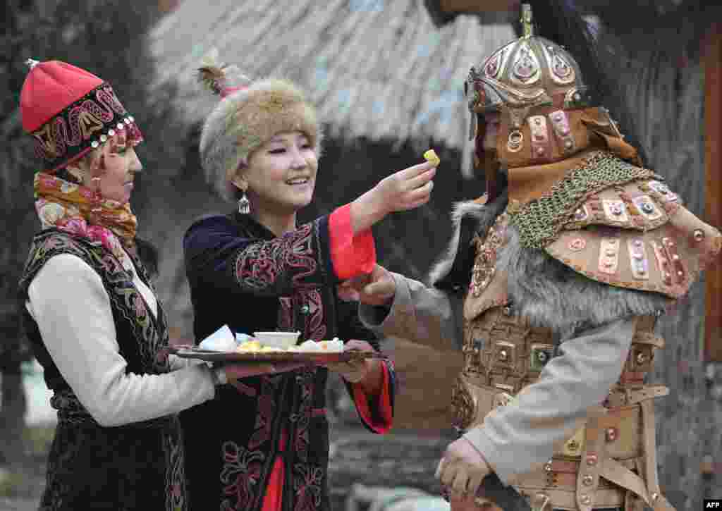 Mengenakan kostum tradisional Kirgiztan, tiga warga Kirgizstan ini merayakan Nowruz (tahun baru) di pinggiran ibukota Kirgizstan, Bishkek. 