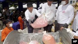 Pegawai Departemen Kesehatan Publik Thailand melempar metamfetamin hasil sitaan ke keranjang sebelum membakarnya. (Foto: Dok)