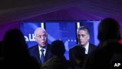 People watch a televised debate between presidential candidates Kais Saied, left, and Nabil Karoui, on the last day of campaigning before the second round of the country's presidential elections, in Tunis, Tunisia, Oct. 11, 2019.