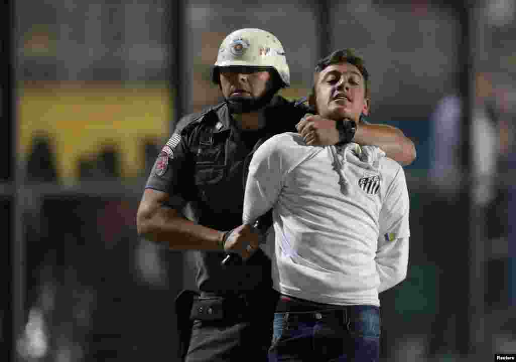 A police officer arrests a Santos soccer fan during a match against Independiente in Sao Paulo, Brazil, Aug. 28, 2018.