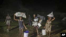 Penyintas gempa berjalan di tengah hujan tropis Grace di kamp pengungsi Les Cayes, Haiti, Senin, 16 Agustus 2021. (AP Photo/Joseph Odelyn)
