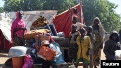 FILE - Cameroonians who fled deadly intercommunal violence between Arab Choa herders and Mousgoum and Massa farming communities stand beside their makeshift shelters on the outskirts of Ndjamena, Chad, Dec. 13, 2021.