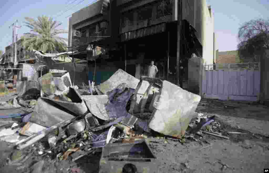 A man inspects the aftermath of a car bomb attack in the neighborhood of Shaab in Baghdad, Iraq, July 3, 2013.