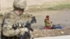 An Afghan girl washing clothes in a river looks at a US Army soldier in the town of Senjaray, southern Afghanistan May 29, 2012.