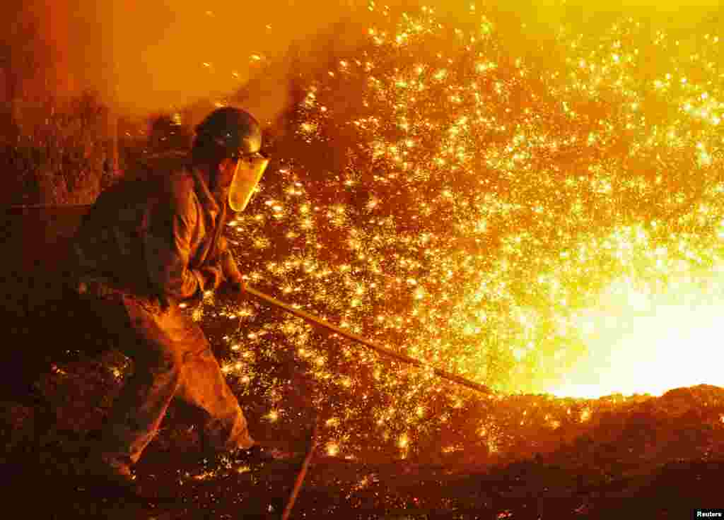 An employee works next to molten iron at a steel mill of Dongbei Special Steel in Dalian, Liaoning province, China.