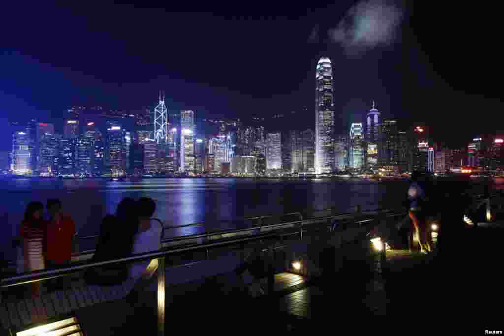 Warga Hong Kong dan wisatawan beristirahat di sepanjang tepi pelabuhan Victoria yang menghadap ke kota Hong Kong, China pada malam hari.