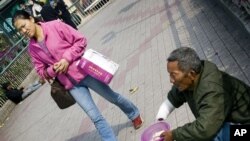 一名妇女走过广州街头的一名乞丐(资料照片)