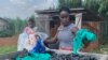 Aweko Faith, right, and Rachel Mema sort through polythene bags for washing, in Mpigi district, Uganda. (H. Athumani/VOA) 