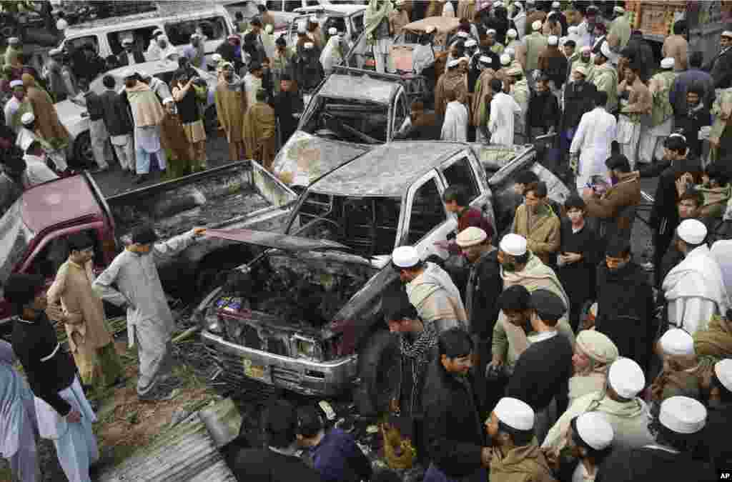 People look at damaged vehicles after a bomb blast in the Pakistani tribal area of Khyber, December 17, 2012. 