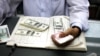 A man counts US dollars and Burma kyats at a money changer in Rangoon, March 21, 2012. 