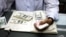 A man counts US dollars and Burma kyats at a money changer in Rangoon, March 21, 2012. 