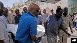 People remove a dead body after a vehicle bomb attack on a security checkpoint located near the presidential palace, in Mogadishu, Somalia, Jan. 8, 2020. 