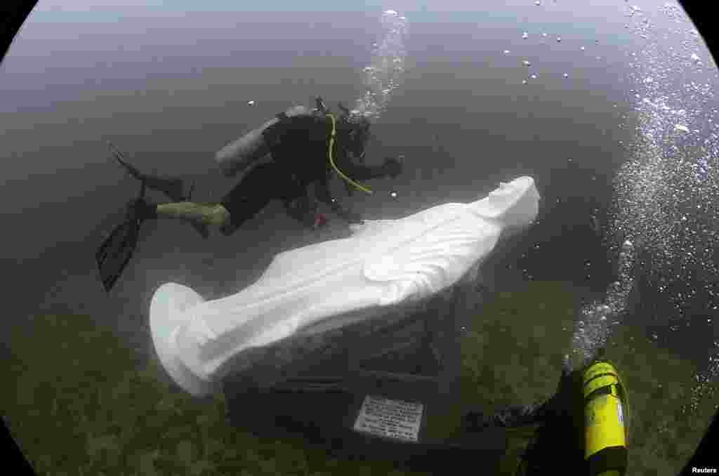 A diver from the diving school &quot;Dive Nicaragua&quot; takes pictures of a statue of the Miraculous Medal Virgin after it was buried in the deep sea at San Juan del Sur town, Nicaragua, Oct. 8,2016.