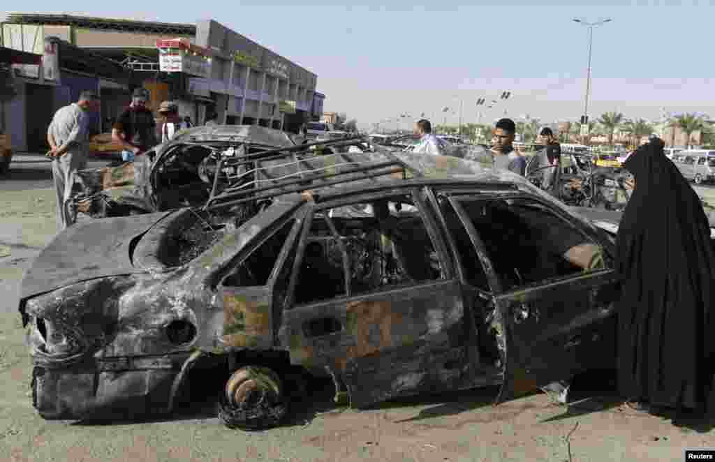A woman inspects a burnt car at the site of a car bomb attack in Hurriya neighborhood in Baghdad July 3, 2013.