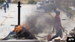 A man walks past burning barricades during a farm workers strike in De Doorns, South Africa, November 14, 2012.