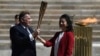 Hellenic Olympic Committee President Spyros Capralos, left, gives the Olympic torch to the former Japanese swimmer Imoto Naoko during the Olympic flame handover ceremony for the 2020 Tokyo Summer Olympics, in Athens, Thursday, March 19, 2020. 
