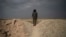 A U.S.-backed Syrian Democratic Forces (SDF) fighter stands atop a hill in the desert outside the village of Baghuz, Syria, Feb. 14, 2019. 