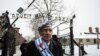 Auschwitz survivor Miroslaw Celka walks out the gate with the sign saying "Work makes you free" after paying tribute to fallen comrades at the "death wall" execution spot in the former Auschwitz concentration camp in Oswiecim, Poland, Jan. 27, 2014.