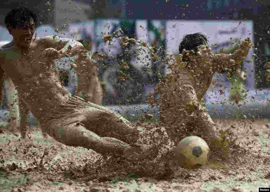 Pemain berebut bola dalam turnamen bola lumpur di Beijing, China. 