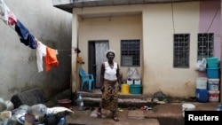 FILE - A 70-year-old woman who fled violence in the northwestern division of Momo poses for a photograph near the house where she has taken refuge in Yaounde, Cameroon, Oct. 2, 2018. 