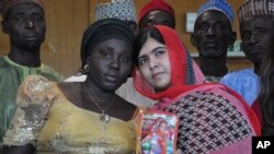 Aktivis Pakistan Malala Yousafzai yang ditembak dan hampir terbunuh oleh Taliban Pakistan karena upayanya menggalakkan pendidikan bagi perempuan dan anak-anak perempuan, memegang foto siswa yang diculik Sarah Samuel bersama ibunya Rebecca Samuel, dalam kunjungan ke Abuja, Nigeria, 13 Juli 2014. 
