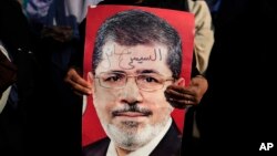 A supporter holds a poster of Egypt's Islamist President Mohammed Morsi with Arabic that reads, "Sisi traitor," during a rally, in Nasser City, Cairo, Egypt, July 4, 2013. 