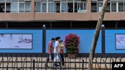 2020 年 9 月 28 日，戴着口罩的行人从仍然关闭的武汉华南海鲜批发市场旁走过。（法新社)