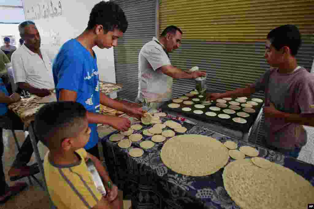 Para pedagang Palestina menjual semacam martabak yang biasanya berisi keju atau kacang, di kota Jenin, Tepi Barat (29/6). (AP/Mohammed Ballas)