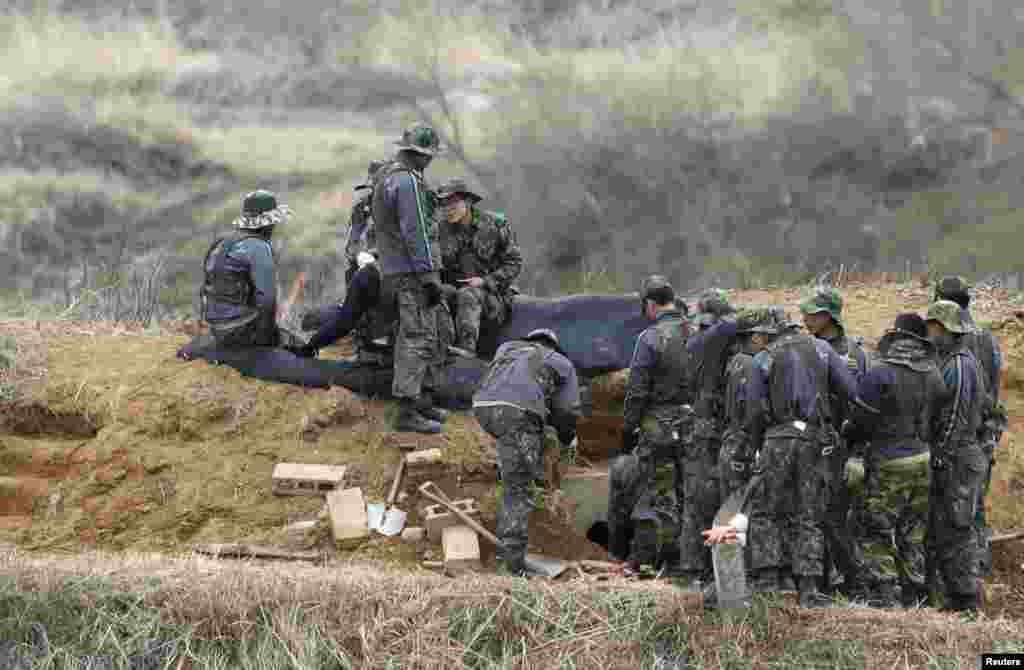 2013年4月15日，韩国士兵在分隔朝鲜半岛南北方的非军事区附近一边聊天一边修整战壕。