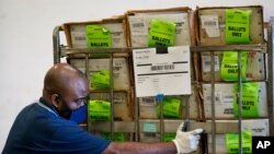 A Miami-Dade County Elections Department employee loads a cart of vote-by-mail ballots into a truck for transport to a local U.S. Postal Service office, Oct. 1, 2020, in Doral, Florida.