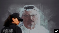 资料照片：在人们在沙特驻伊斯坦布尔领事馆附近举行周年纪念仪式之前，一名土耳其警察走过遇害记者卡舒吉的画像。(2019年10月2日)