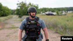 ທີ່​ປຶກ​ສາ​ດ້ານ​ຄວາມ​ປອດ​ໄພ​ຂອງ​ອົງ​ການ​ຂ່າວ ຣອຍ​ເຕີ ທ່ານ ຣາຍ​ແອນ ເອ​ແວນ​ສ໌ ຢືນ​ຢູ່​ໃນ​ສະ​ໜາມ​ລົບ ໃນ​ຂະ​ນະ​ທີ່​ເຮັດ​ວຽກ​ກັບ​ທີມ​ຂ່າວ​ໃນ ຢູ​ເຄ​ຣນ.