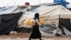 A woman carries jerry cans to fill them up with water at the Kurdish-run al-Hol camp for the displaced where families of Islamic State (IS) foreign fighters are held, in the al-Hasakeh governorate in northeastern Syria on Dec. 9, 2019.