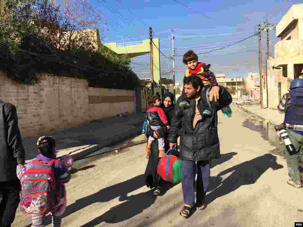 Wani mutum dauke da dansa a kafada da sauran iyalinsa kan hanyar ficewa daga Mosul, Janairu 13, 2017 &nbsp;