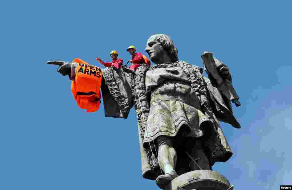 Activists from the Spanish Proactiva Open Arms charity place a life jacket on the Christopher Columbus statue after the Open Arms rescue boat arrived at a port in Barcelona, Spain, carrying migrants rescued off Libya.