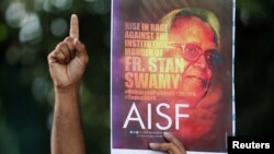 A man gestures as he holds a placard during a protest to show solidarity with a Christian priest and an activist Father Stanislaus Lourduswamy, Mumbai, India, July 7, 2021.