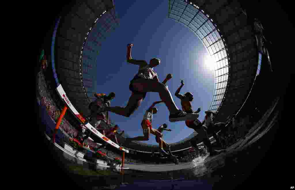 Athletes clear the water in a men's 3000-meter steeplechase heat at the European Athletics Championships at the Olympic stadium in Berlin, Germany.