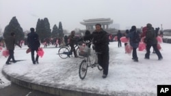 지난달 22일 북한 평양에서 건군절 열병식 연습에 참가한 주민들이 붉은 조화다발을 들고 집으로 돌아가고 있다. (자료사진)