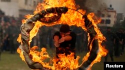 Seorang warga Palestina melompat ke dalam lingkaran api sebagai tanda kelulusan sebuah pendidikan ala militer di Gaza, 14/1/2014.