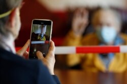 FILE - Marguerite Mouille, 94, gestures while her visiting daughter takes a photo at the Kaisesberg nursing home, eastern France, April 21, 2020.
