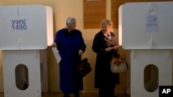 Dua warga Moskow di sebuah TPS untuk memberikan suara dalam pemilihan walikota Moskow, Minggu (8/9).