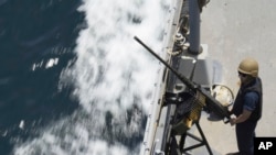 资料图片：2023年5月19日星期五，一名美国海军水手在霍尔木兹海峡的保罗·汉密尔顿号航空母舰上的机枪旁站岗。 (美联社图片)