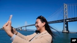 Content creator Cynthia Huang Wang works below the San Francisco-Oakland Bay Bridge in San Francisco, Monday, April 8, 2024. (AP Photo/Eric Risberg)