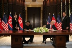 FILE - U.S. President Donald Trump and North Korea's leader Kim Jong Un sign documents that acknowledge progress in talks and pledge to keep momentum going, after their summit at the Capella Hotel on Sentosa island in Singapore, June 12, 2018.
