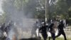 Liberian police advance past burning barricade as they chase opposition party supporters in Monrovia, Nov. 7, 2011.