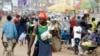 FILE - A man wearing a Cameroon soccer jersey walk past a busy Mokolo Market in Yaounde, Cameroon.