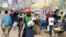 FILE - A man wearing a Cameroon soccer jersey walk past a busy Mokolo Market in Yaounde, Cameroon.