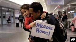 Thy Chea, of Lowell, Mass., center right, originally of Cambodia, hugs his daughter on his arrival at Boston's Logan Airport, Wednesday, Feb. 26, 2020, after getting his green card reinstated last year. 