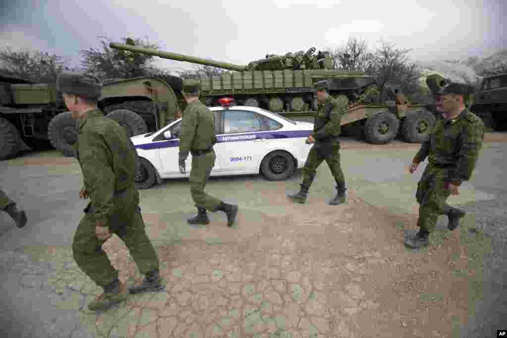 Russian police cars drive and Ukrainian soldiers walk behind Ukrainian tanks at Perevalnoe, outside Simferopol, Crimea, March 26, 2014.