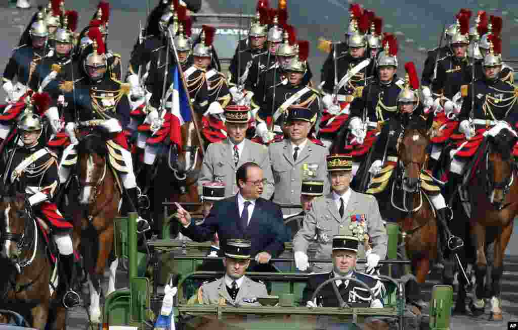 Presiden Perancis Francois Hollande (berdiri, kiri), &nbsp;di atas mobil dalam parade Hari Bastille di Champs-Elysees, Paris (14/7). (AP/Francois Mori)